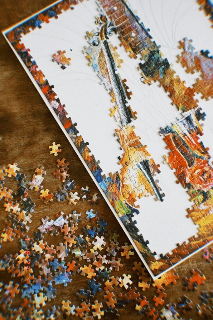 Top view of a partially assembled colorful jigsaw puzzle on a wooden surface with scattered pieces.